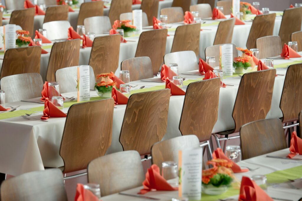 banquet-wedding-society-deco-50675-50675 Beautifully arranged tables with wooden chairs for a formal event, adorned with orange flowers.